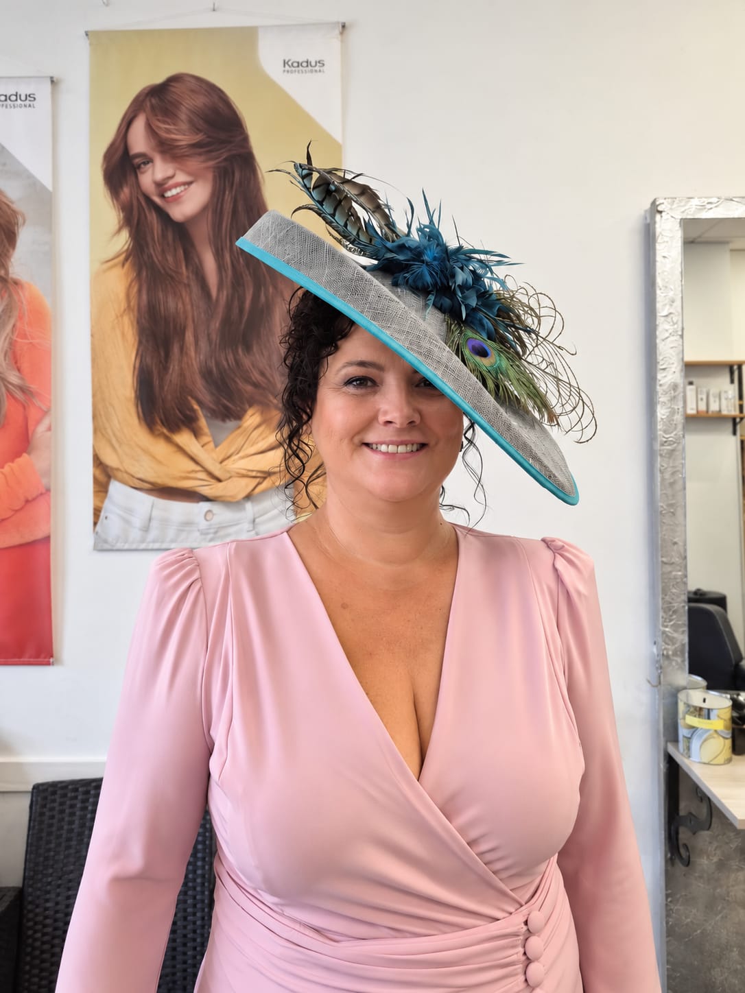 Invitada sonriente con peinado y sombrero azul con plumas